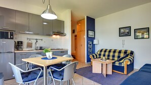A compact living space with a kitchenette, a dining area with a table and chairs, and a sofa. - Scenic Apartment With Garden in Medulin (Medulin)