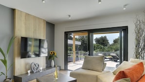 A modern living room with a flat-screen TV, a coffee table, and a sofa with cushions. - Comfortable, Stylish, Detached Villa With Garden, Private Pool, Near the Beach (Medulin)