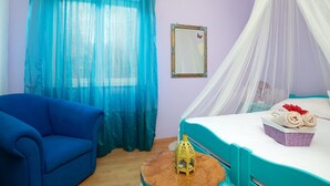 A bedroom with a bed, a blue armchair, a wooden table, a mirror, and a window with sheer curtains. - Alluring Apartment in Medulin near Beach (Medulin)