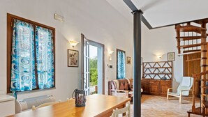 A spacious living area with a wooden dining table, white chairs, a sofa, and a staircase. - Cozy Tuscan Getaway (Fucecchio)