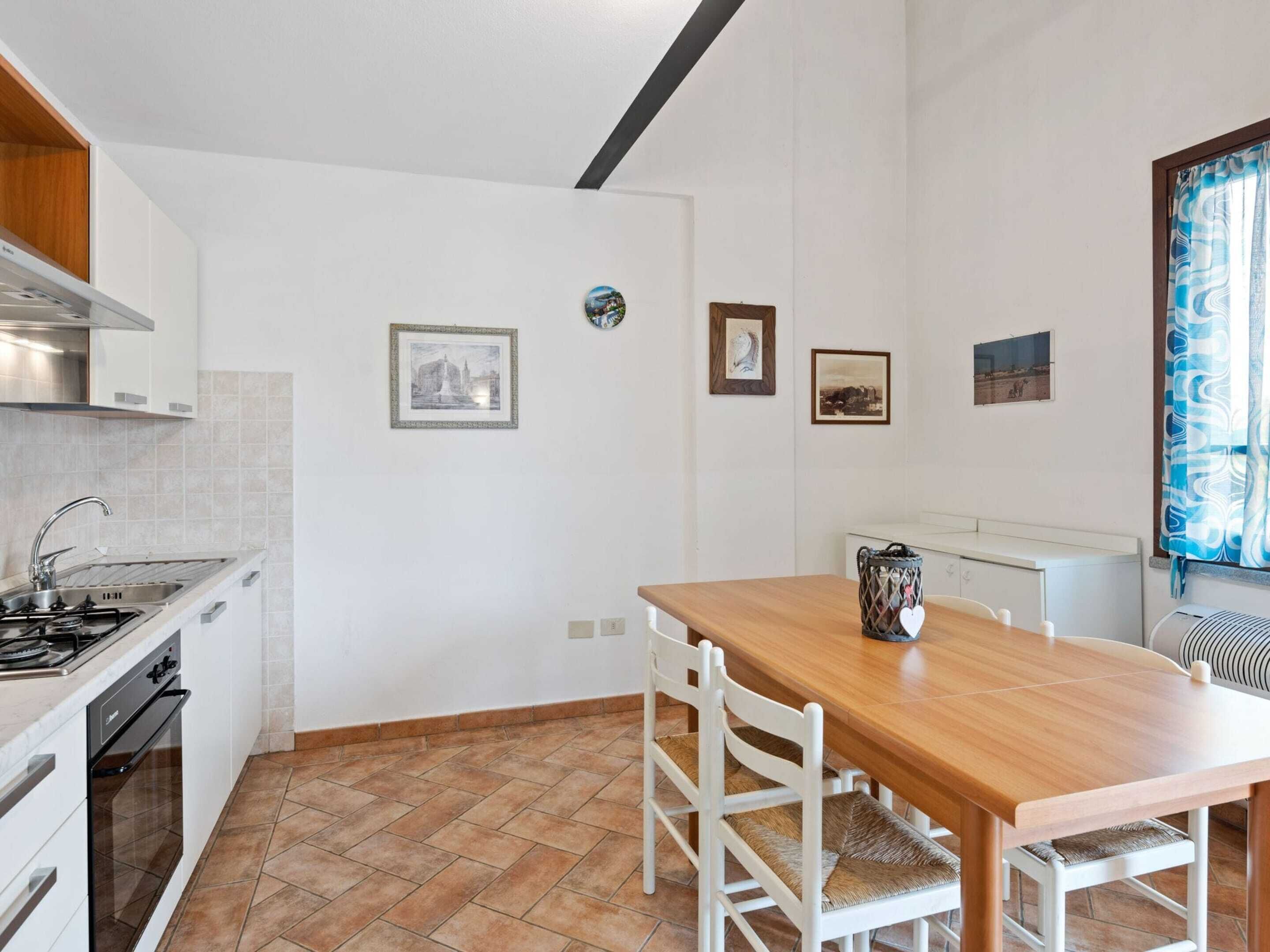 Une cuisine moderne avec des meubles blancs, une table à manger en bois et un sol carrelé.