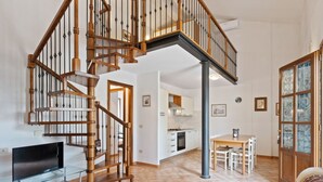 A spacious living area with a wooden staircase, a kitchen, and a dining area. - Cozy Tuscan Getaway (Fucecchio)