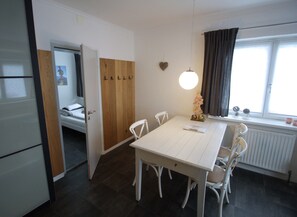 A compact room with a dining table, chairs, a bed, and a window with curtains. - Fabulous Apartment in Bichlbach (Bichlbach)
