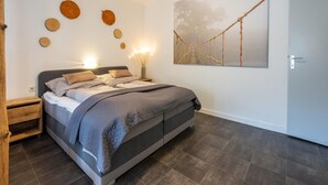A bedroom with a bed, bedside tables, a wall-mounted artwork, and a door. - Fabulous Apartment in Bichlbach (Bichlbach)