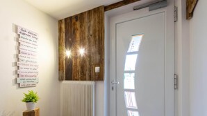 A room with a wooden wall, a white door with frosted glass panels, a radiator, and a small table with a plant. - Fabulous Apartment in Bichlbach (Bichlbach)