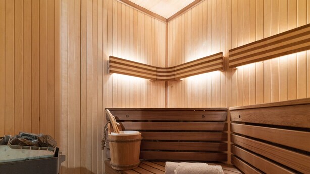 A sauna with wooden benches and a bucket.