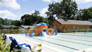 An outdoor swimming pool with a large octopus water feature, lounge chairs, and a wooden building in the background.