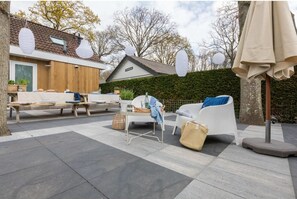 An outdoor patio area with a dining table, chairs, and a sofa.
