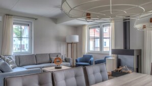 A modern living room with a sofa, chairs, a dining table, and a fireplace. - Luxury Villa near Sea (Kamperland)