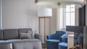 A modern living room with a grey sofa, a blue armchair, and a floor lamp. - Luxury Villa near Sea (Kamperland)