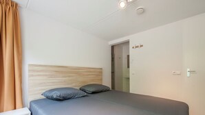 A modern bedroom with a wooden headboard, a grey bedspread, and two pillows. - Luxury Villa near Sea (Kamperland)