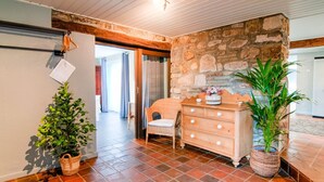 A cozy room with a stone wall, a wicker chair, a wooden dresser, and a potted plant.