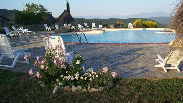 A pool area with lounge chairs and a stone patio. - Farmhouse in Monticiano Near Petriolo Spa (Monticiano)