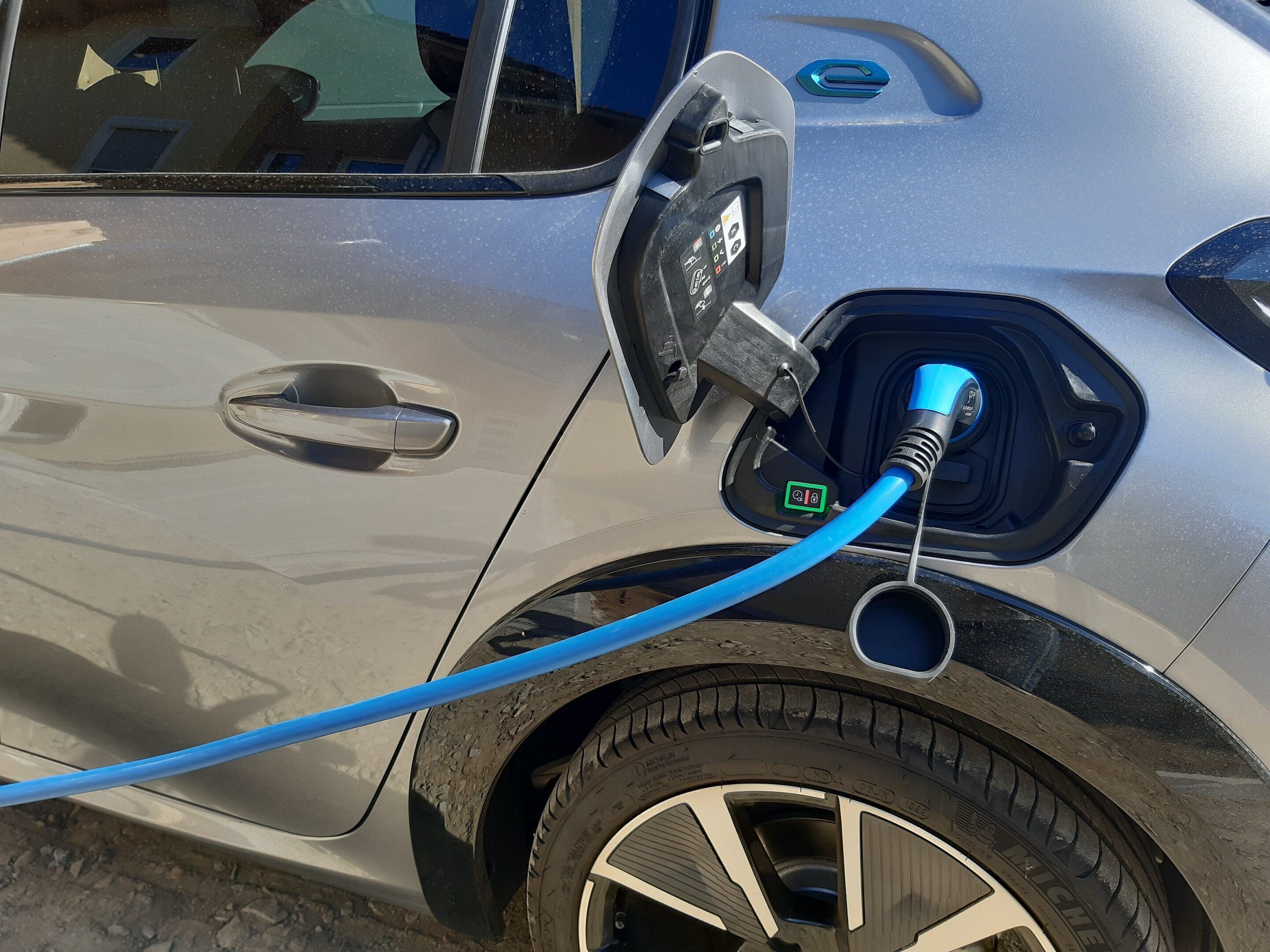 Une voiture avec un câble de recharge branché à une prise de recharge située sur le côté.