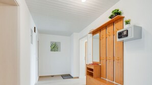 A hallway with a wooden wardrobe, a small plant, and a wall-mounted heater. - Sunny, Modern Furnished Apartment Your Favourite Place to Relax (Viechtach)