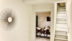 A dining area with a modern chandelier, a staircase, and a wall-mounted mirror. - Elegant Holiday Home in Nieuwpoort near Beach (Nieuwpoort)