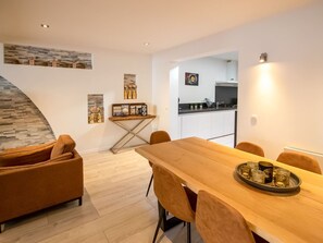 A modern dining area with a wooden table and chairs, a small kitchen in the background, and decorative items on the walls. - Elegant Holiday Home in Nieuwpoort near Beach (Nieuwpoort)