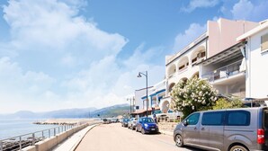 A coastal road with parked cars, a clear sky, and buildings with balconies. - Sprawling Apartment in Cala Gonone near Cala Fuili Beach (Dorgali)