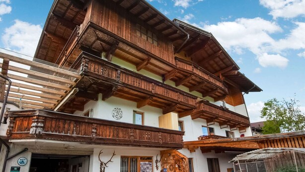 Un chalet de madera tradicional con un balcón y una cabeza de ciervo montada.
