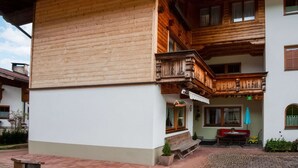 Un edificio de madera de dos pisos con un balcón, un banco y una pequeña mesa con una silla.