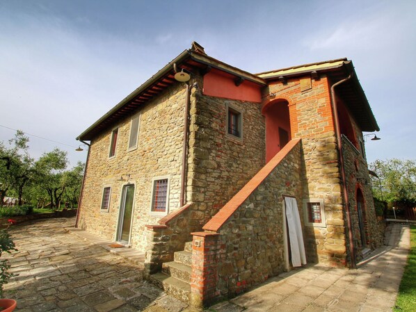 A stone building with a red roof, a staircase, and a door.