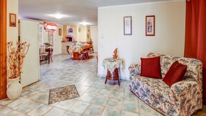 Amplia sala de estar con un sofá estampado, una mesa de comedor y una cocina al fondo.