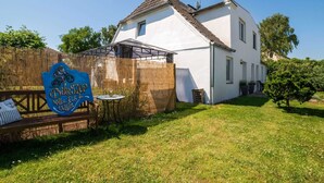 Una casa bianca con patio coperto, recinzione in legno e un cartello che riporta 'Bike Star Coffee, Eis & Co'.