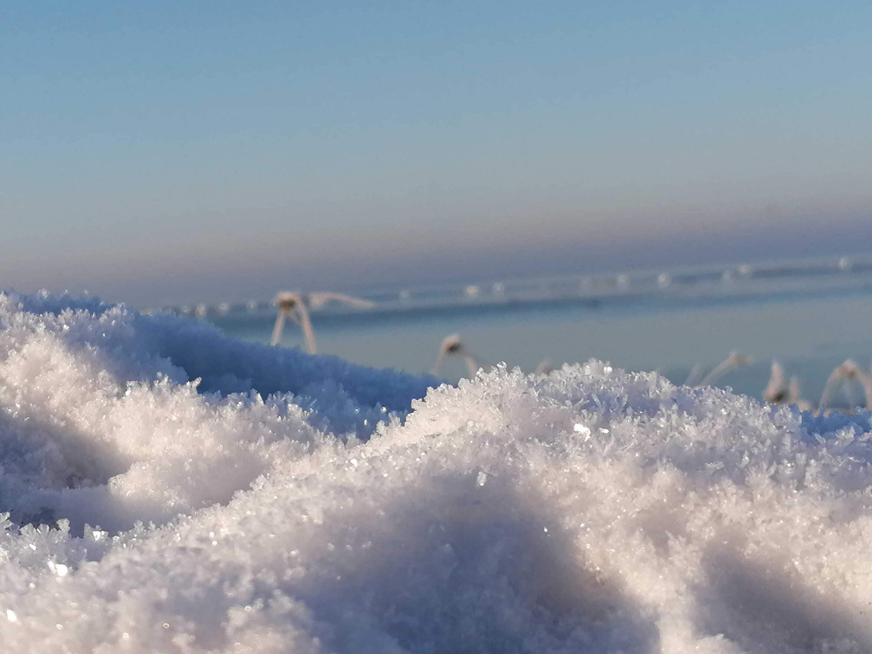 Primer plano de nieve con un fondo borroso de cielo despejado.