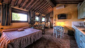 Une chambre rustique comprenant un lit, une petite table, une chaise et un coin cuisine.