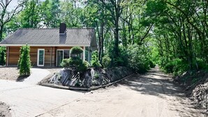 A single-story house with a tiled roof, a front porch, and a paved driveway. - House in Reutum With Jacuzzi & Forest View (Reutum)