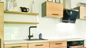 A modern kitchen with wooden cabinets, a built-in oven, a microwave, and a sink with a black faucet. - House in Reutum With Jacuzzi & Forest View (Reutum)