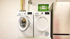 A front-loading washing machine and dryer unit with a stainless steel refrigerator to the right. - House in Reutum With Jacuzzi & Forest View (Reutum)