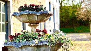 A multi-tiered stone fountain with plants, located outdoors in front of a building.