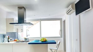 Una cocina moderna con una isla central, estufa integrada y un amplio ventanal que proporciona luz natural.