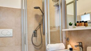 Un baño moderno con ducha de vidrio, un lavamanos blanco y un espejo sobre él.
