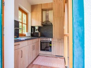 Cocina compacta con armarios de madera, horno empotrado y ventana que proporciona luz natural.