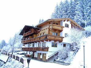 A multi-story wooden chalet with balconies, set in a snowy mountainous area. - Apartment in Gerlosberg Near Ski Lift (Gerlosberg)