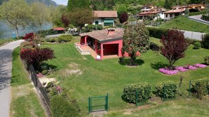 A house with a red exterior, a covered patio, and a view of a lake and mountains. - Villa by Lake Idro With Panoramic Views (Idro)