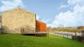 A stone building with a wooden deck and a fenced area. - Magnificent Holiday Home in Manhay With Fenced Garden (Manhay)