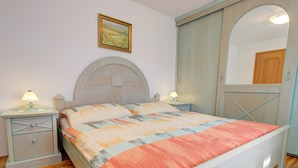 A bedroom with a bed, nightstands, a lamp, a painting, and a wardrobe. - Lovely Apartment in Bled near Lake (Bled)