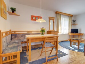 A cozy living room with a wooden bench, a dining table, and a TV.