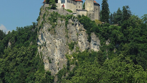 Un château perché au sommet d’une falaise rocheuse, entouré d’une végétation luxuriante.