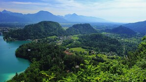 Un paysage montagneux avec un lac, des collines boisées et une petite ville.