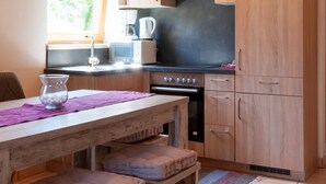 Eine kleine Küche mit Holzschränken, einem eingebauten Ofen und einem Fenster, das für natürliches Licht sorgt.