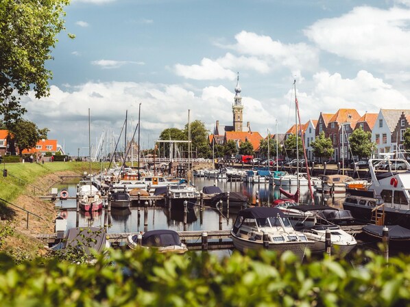 A marina with various boats docked, a church with a tower, and traditional buildings with red roofs. - Luxury Villa by Veerse Meer Lake (Kamperland)
