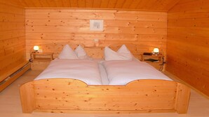 Een kamer met houten vloeren, een bed, twee nachtkastjes en een hanglamp.