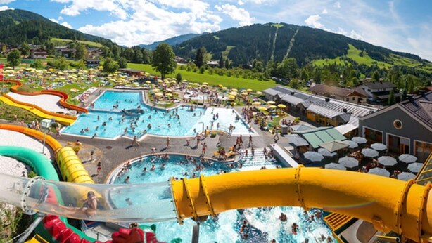 A water park with multiple pools and slides, surrounded by green hills and buildings. - Cozy Holiday Apartment Close to the Slopes (Kleinarl)