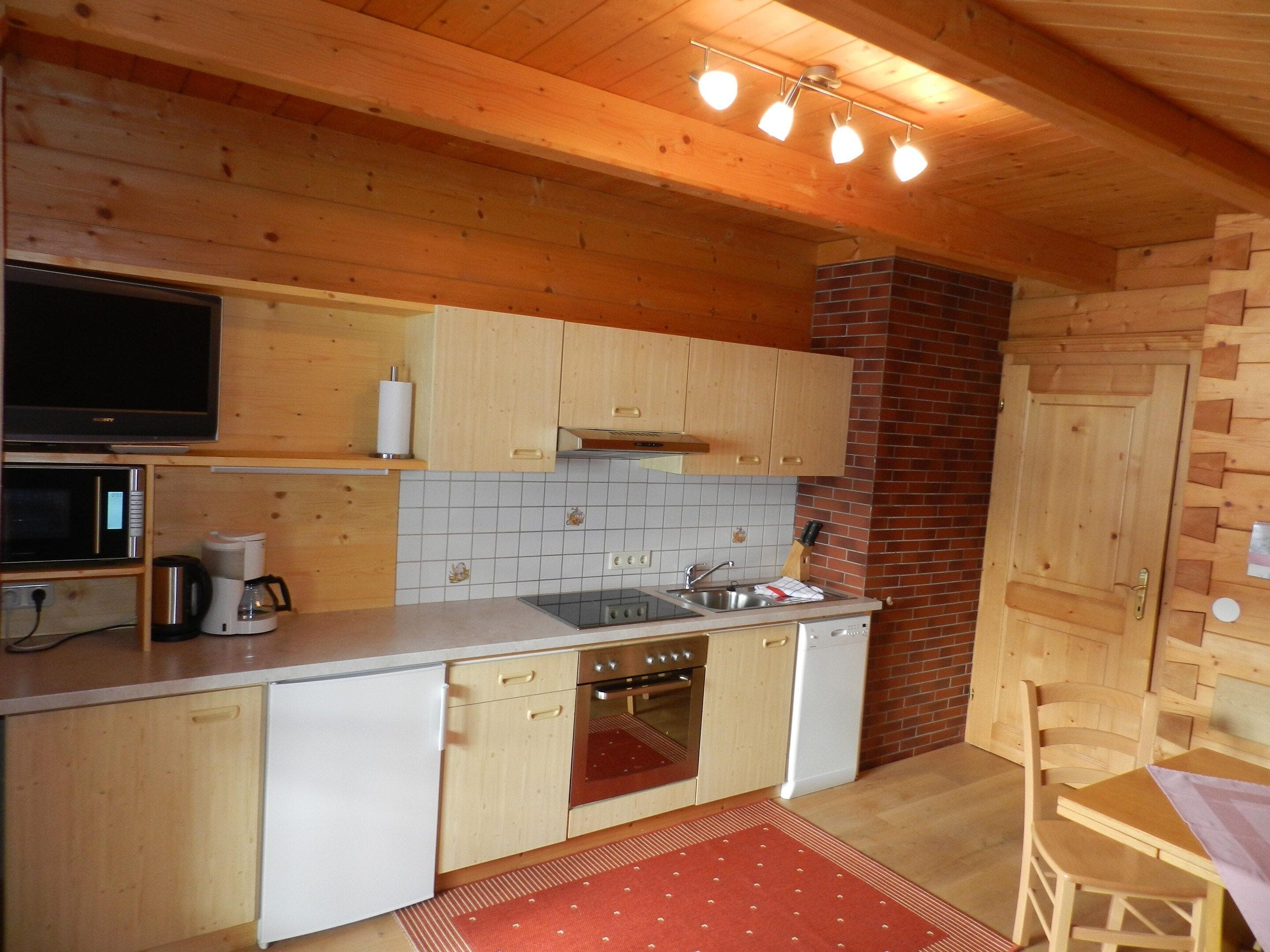 Una cocina compacta con muebles de madera, un microondas, una estufa y un lavavajillas.