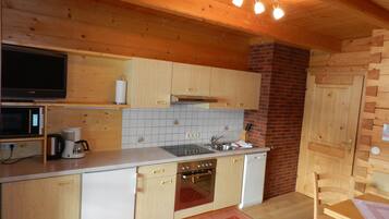 Una cocina compacta con muebles de madera, un microondas, una estufa y un lavavajillas.