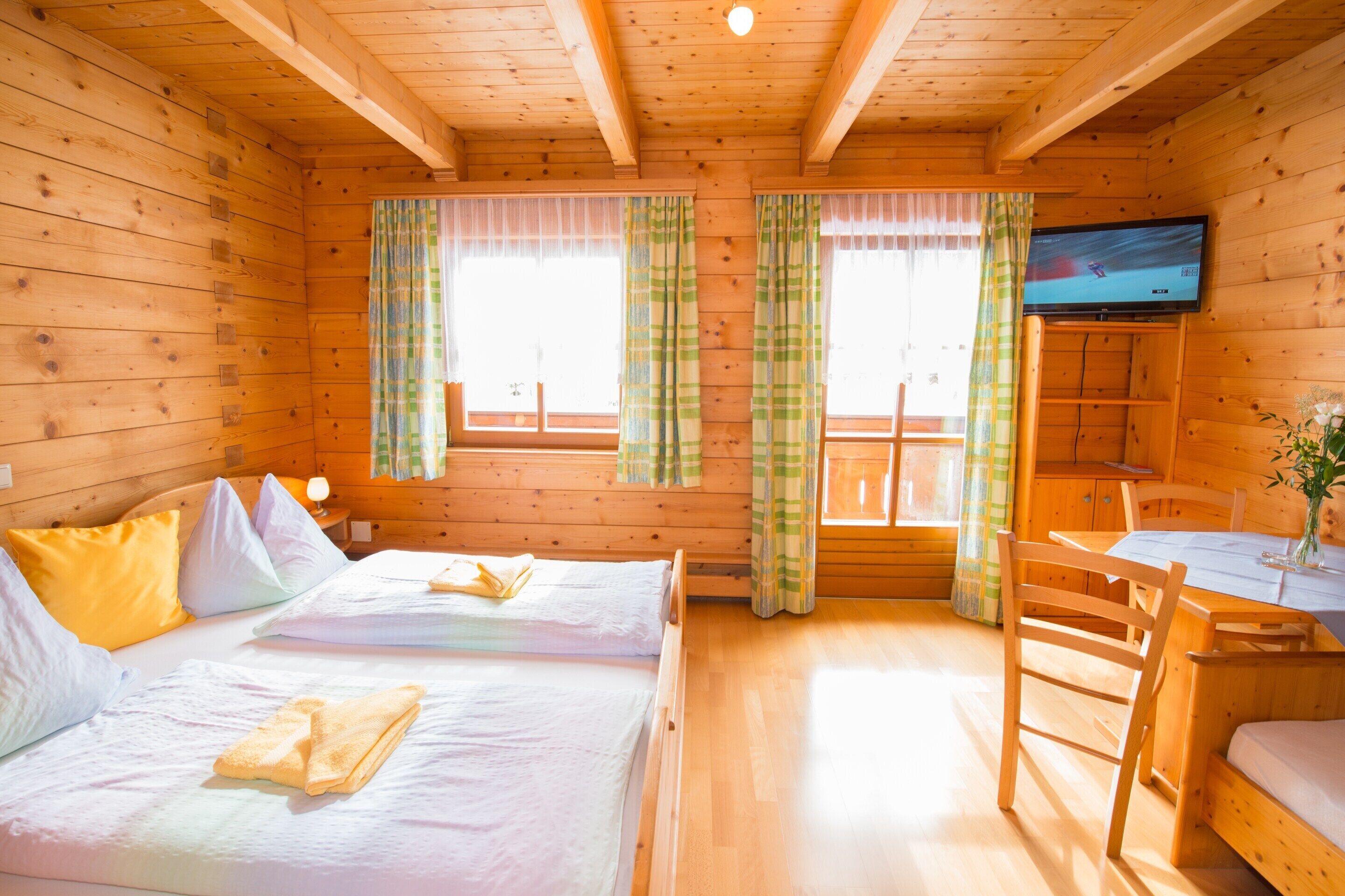 Een hut met twee bedden, een televisie en een eethoek.